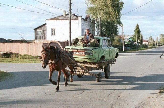 Телега с лошадью везет машину